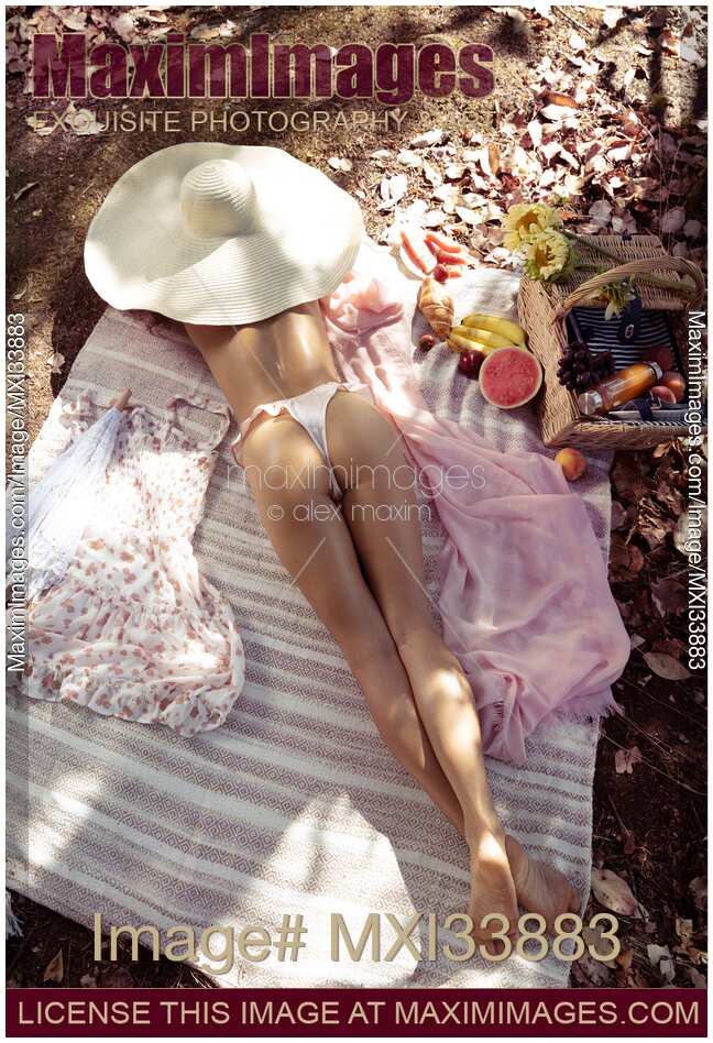 Young woman in sun hat and underwear relaxing topless at a picnic in summer with view on her sexy buttocks and long legs