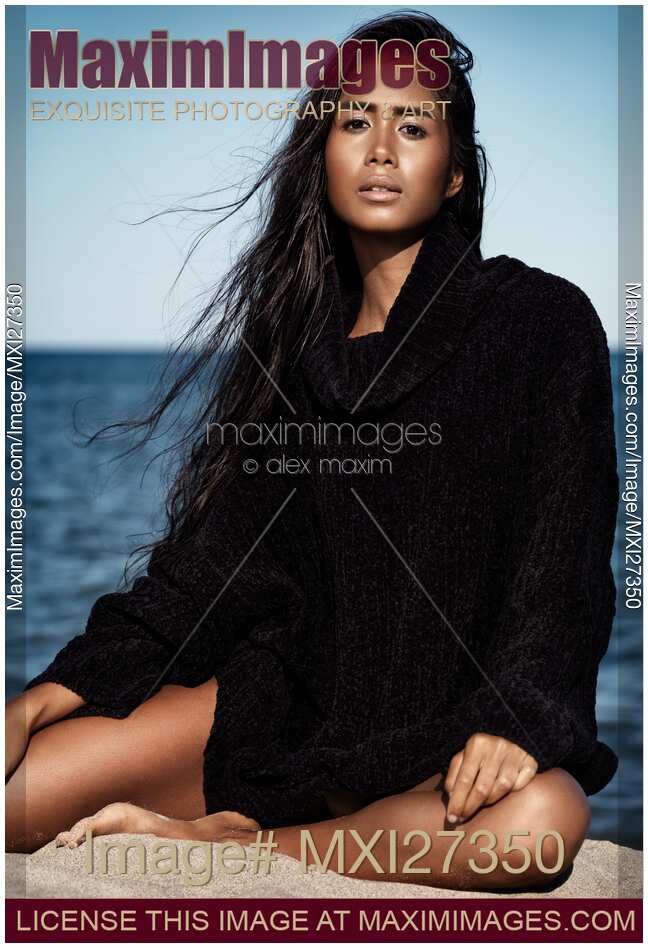 Young woman in sweater sitting at the beach