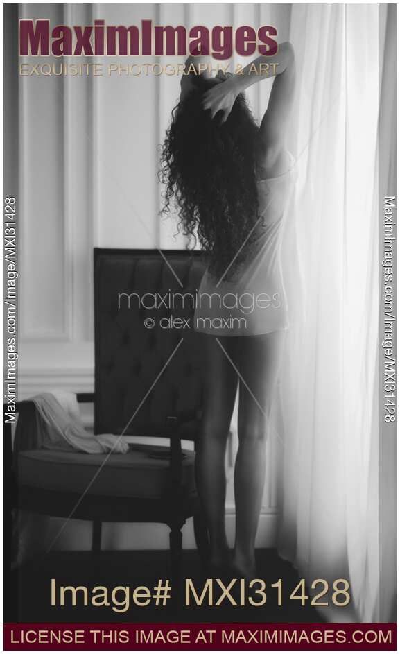 Young woman in underwear with bare legs stretching by the window in morning sunlight Black and white