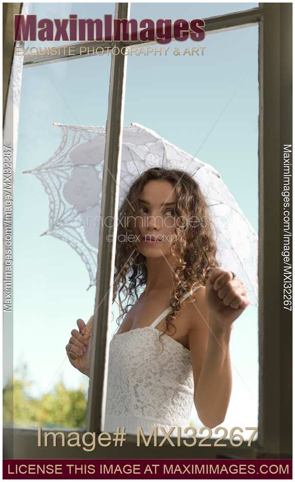 Young woman knocking on the door standing outside the house in summer dress with a French lace parasol