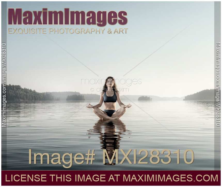 Young woman meditating on platform in the water