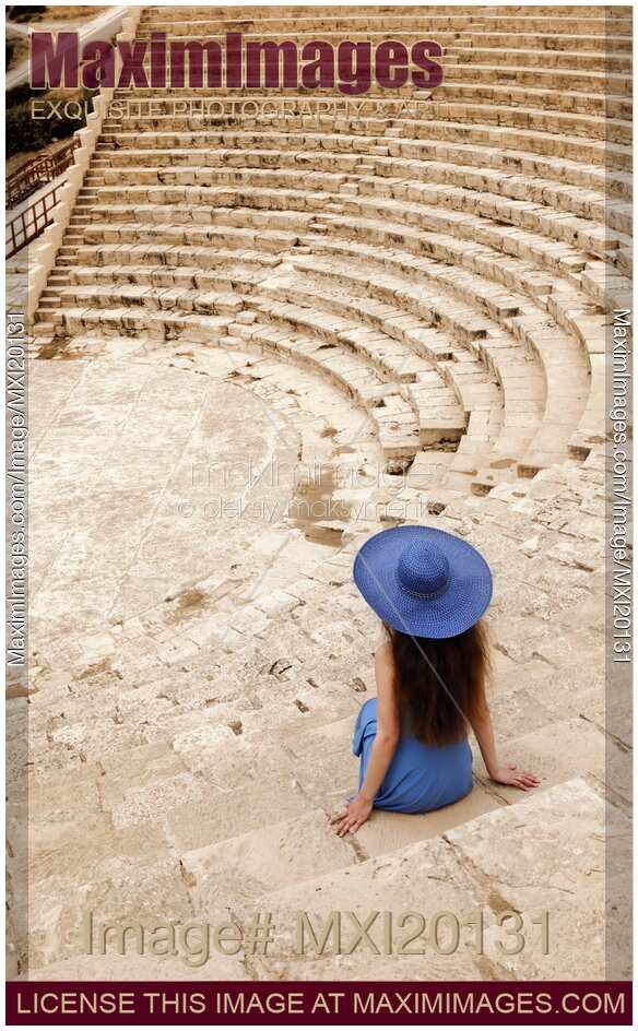 Young woman sitting alone on steps of historic amphitheatre