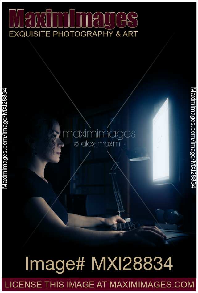 Young woman sitting at night in front of a computer display