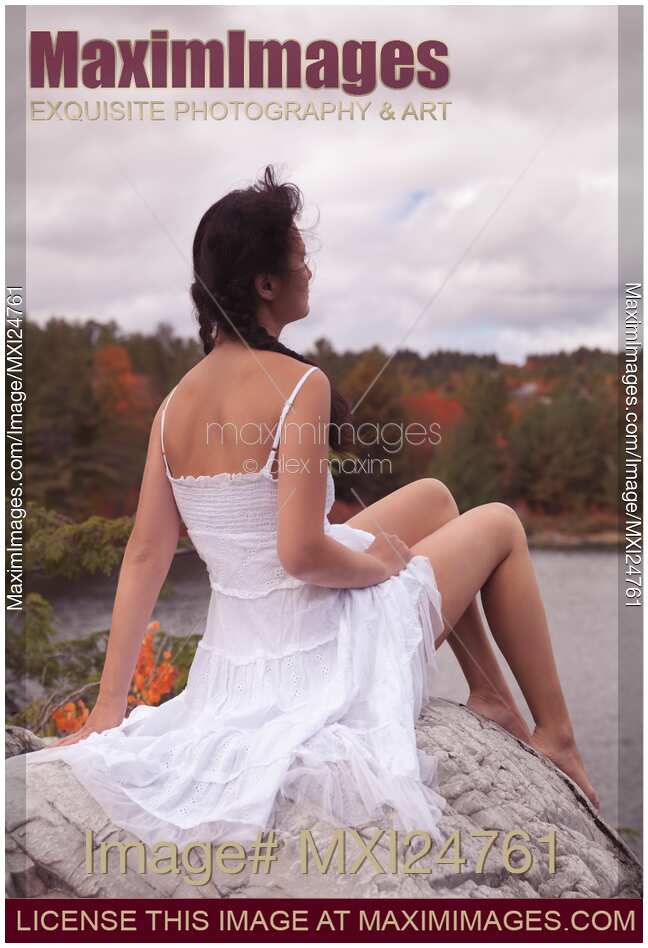 Young woman sitting on a rock near a lake