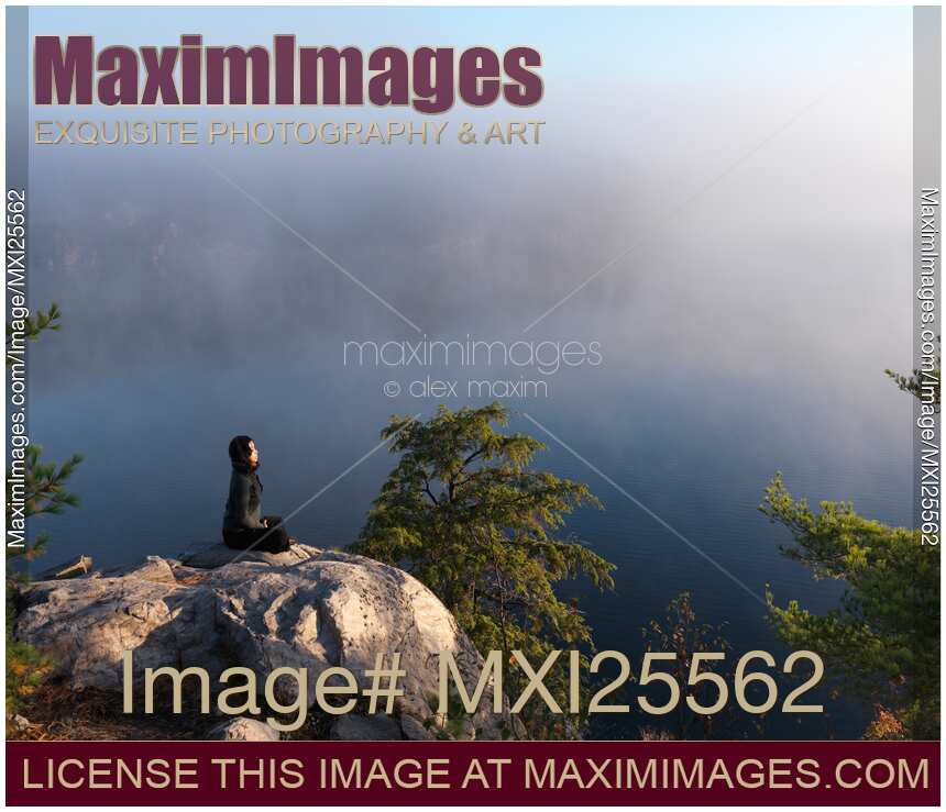 Young woman sitting on rock meditating