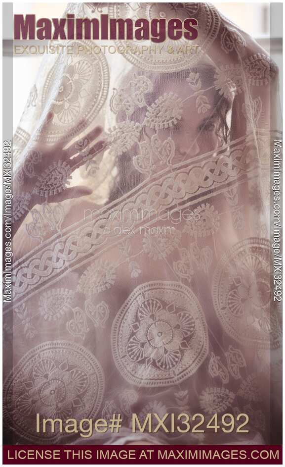Young woman undressing looking through sheer white lace nightgown covering her face and naked body