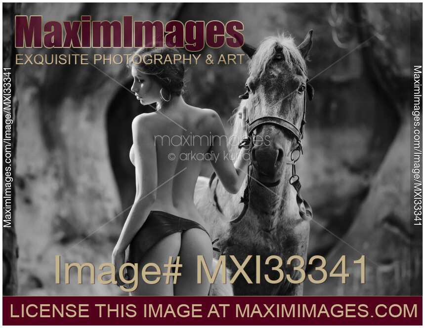 Young woman walking half naked with a horse in the forest rear view of her back and buttocks
