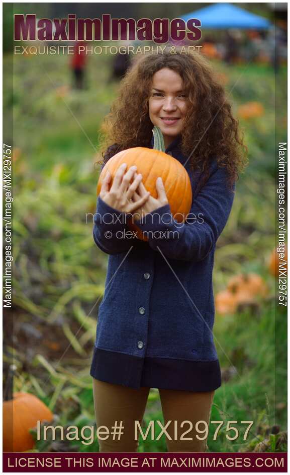 Young woman with a pumpkin at a farm in fall