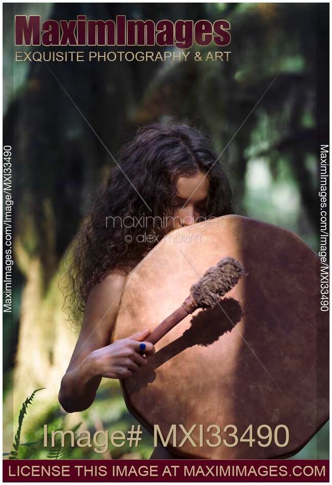Young woman with a shamanic drum in a tranquil forest scenery