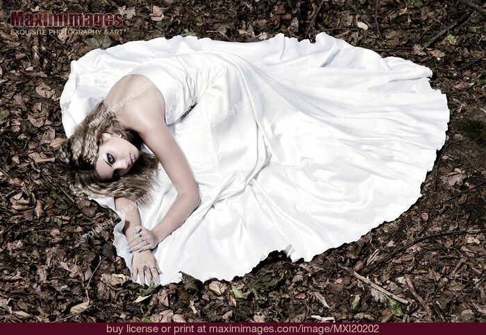 Stock photo of Beautiful Bride in Wedding Gown Lying on Fallen Autumn Leaves Buy commercial use license at MaximImages