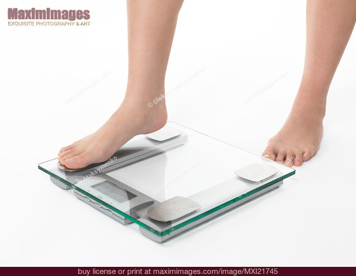Stock photo of Woman Stepping on Weight Scale Buy commercial use license at MaximImages