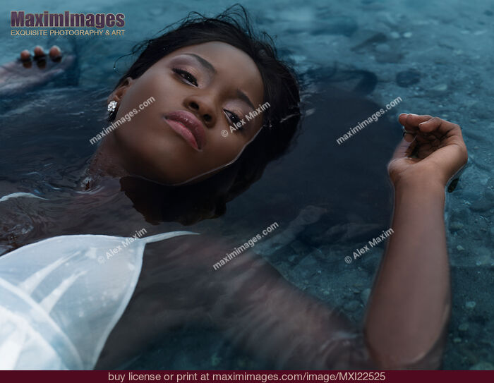 Stock photo of Young Woman in White Dress Lying in Water Buy commercial use license at MaximImages