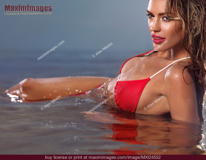 Young glamorous woman in red bikini lying in water. Stock Photo MXI24552