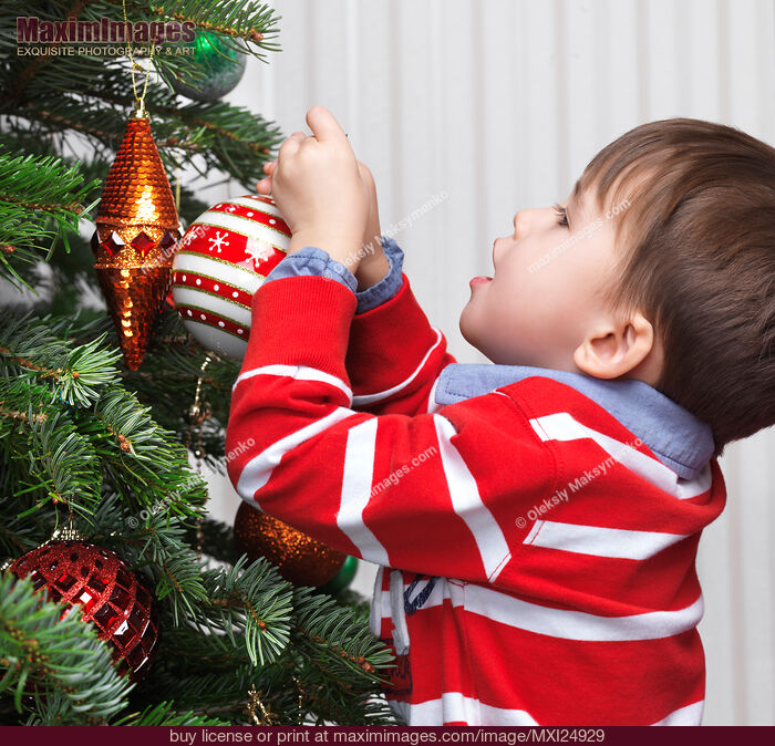 Stock photo of Child decorating a Christmas tree Buy commercial use license at MaximImages