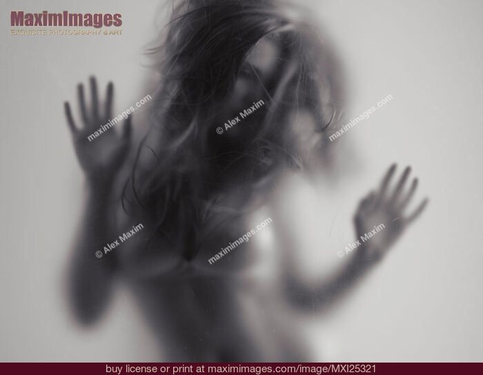 Stock photo of Beautiful young woman behind glass Buy commercial use license at MaximImages