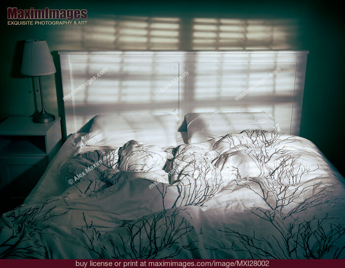 Stock photo of Unmade empty bed in dramatic lighting Buy commercial use license at MaximImages