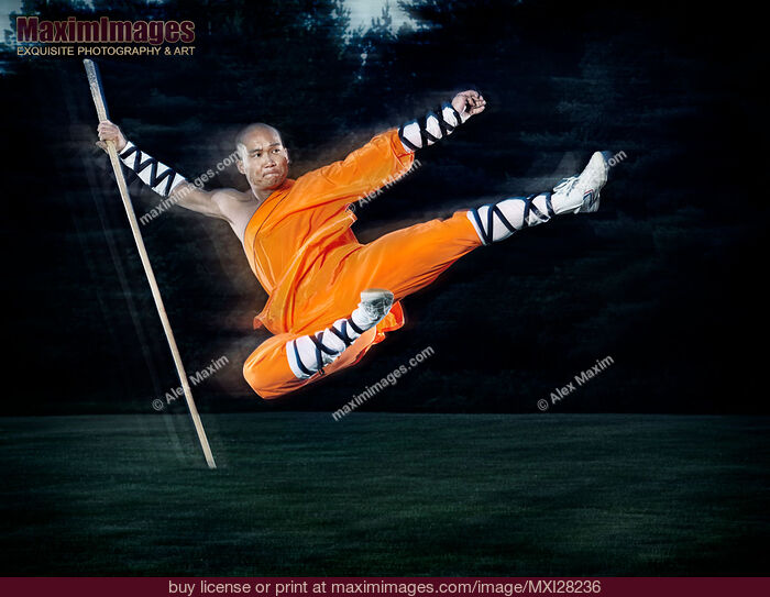 Stock photo of Shaolin warrior monk performing flying kick with a staff Buy commercial use license at MaximImages