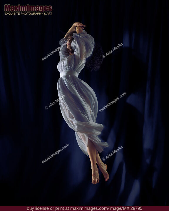 Stock photo of Young woman dancer spinning in the air in light blue dress Buy commercial use license at MaximImages
