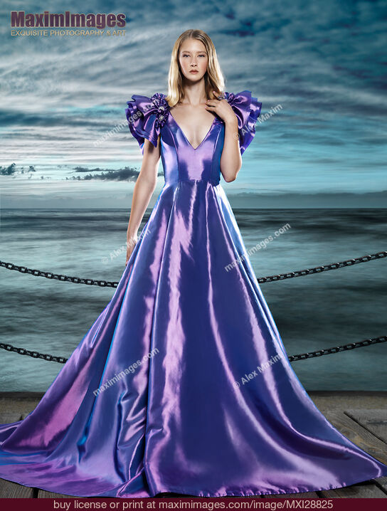 Stock photo of Woman wearing beautiful long blue dress at waterfront Buy commercial use license at MaximImages