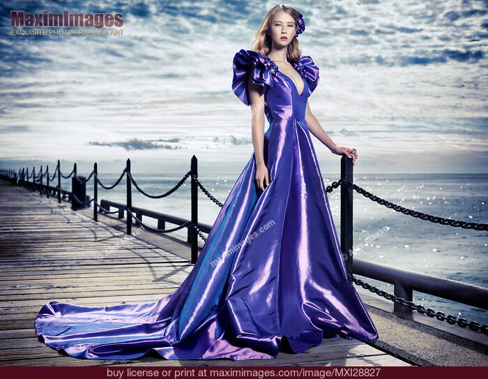 Stock photo of Young woman in beautiful long evening gown at waterfront Buy commercial use license at MaximImages