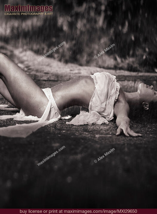 Stock photo of Beautiful sexy young woman in beach wear lying on the ground under pouring rain Buy commercial use license at MaximImages