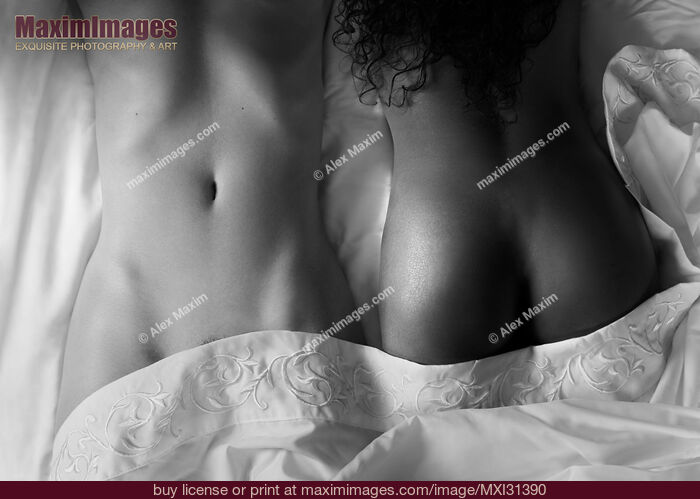 Stock photo of Sexy interracial lesbian couple lying together in bed sensual black and white closeup of two nude bodies Buy commercial use license at MaximImages