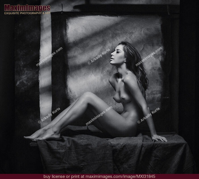 Stock photo of Fine art nude woman sitting naked on a posing table in artist studio Buy commercial use license at MaximImages