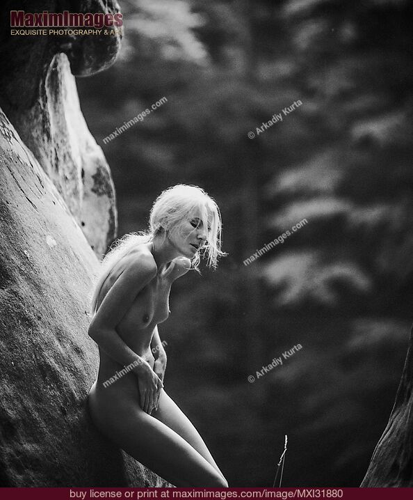 Stock photo of Nude woman with long white hair leaning against the rocks in the nature Buy commercial use license at MaximImages