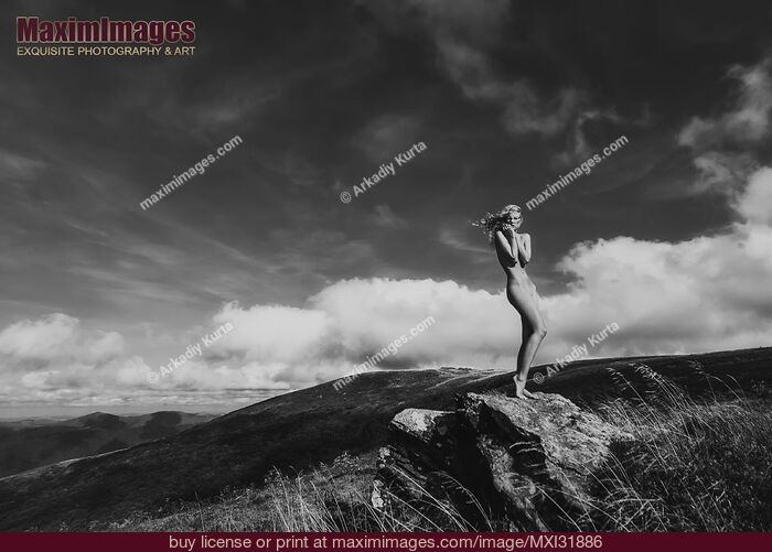 Stock photo of Nude woman standing gracefully on rocks in mountain landscape scenery Black and white Buy commercial use license at MaximImages
