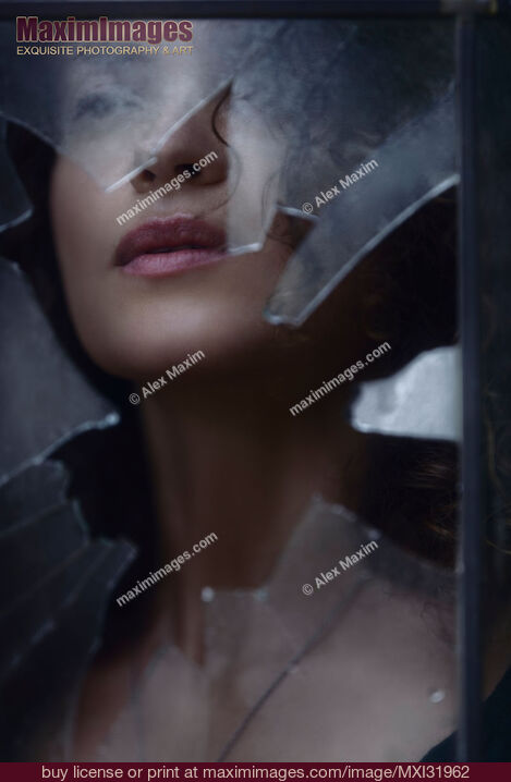 Stock photo of Woman face visible through a hole in a window looking through broken glass Buy commercial use license at MaximImages