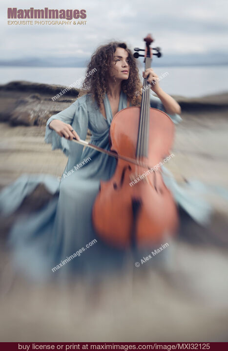 Stock photo of Woman with a nostalgic look playing cello on a sea shore in sunrise scenery Buy commercial use license at MaximImages