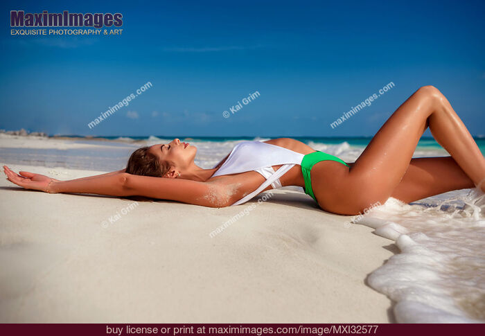 Stock photo of Beautiful sexy sun tanned woman in fashion swimsuit lying on white sandy shore of Caribbean Sea beach in Cancun Mexico Buy commercial use license at MaximImages