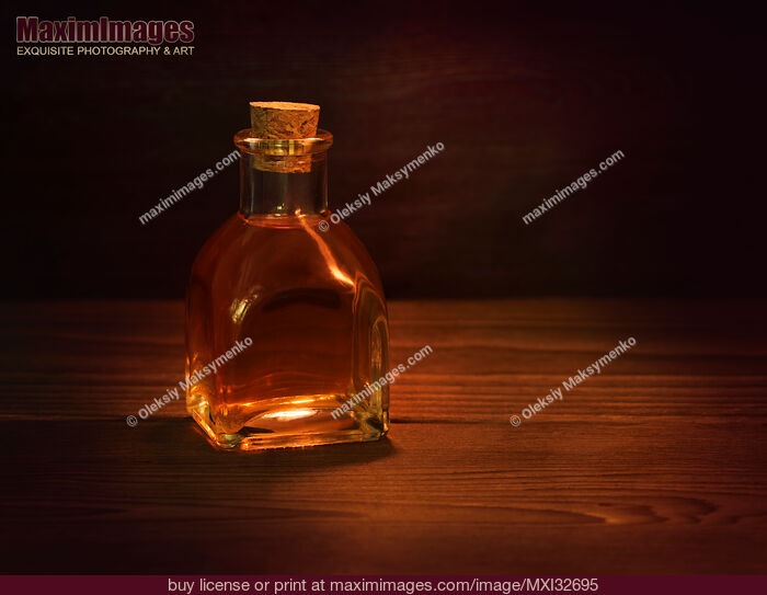 Stock photo of Antique glass bottle with a cork and amber liquid of extract or elixir Still life Buy commercial use license at MaximImages