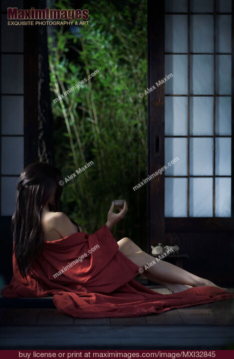 Stock photo of Sexy Asian woman in red kimono drinking tea half undressed by open shoji doors in historic Japanese house Buy commercial use license at MaximImages