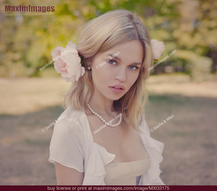 Stock photo of Romantic portrait of a young pretty woman with a pink flower in her blond hair Buy commercial use license at MaximImages