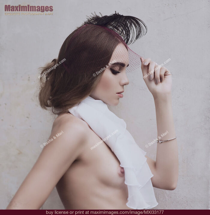 Stock photo of Young woman in a veil headpiece with a feathers and a white scarf barely covering her naked breast Sensual vintage portrait Buy commercial use license at MaximImages
