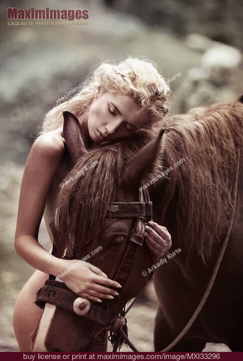 Stock photo of Beautiful naked woman with blond hair hugging a brown horse in the nature Buy commercial use license at MaximImages
