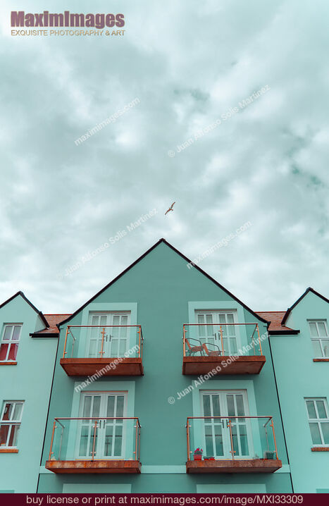 Stock photo of Cute blue residential houses with balconies under blue sky Buy commercial use license at MaximImages