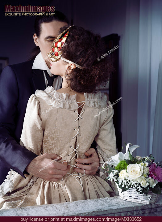 Stock photo of Sensual portrait of a couple, man unlacing corset dress back of a woman in Venetian carnival mask. Casanova romantic seduction concept. Buy commercial use license at MaximImages