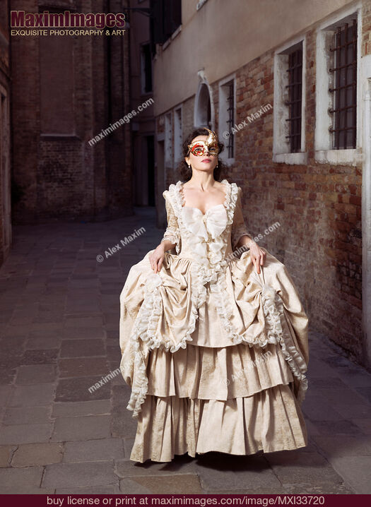 Stock photo of Beautiful lady in vintage Italian dress and carnival mask running along a historic street in Venice Buy commercial use license at MaximImages