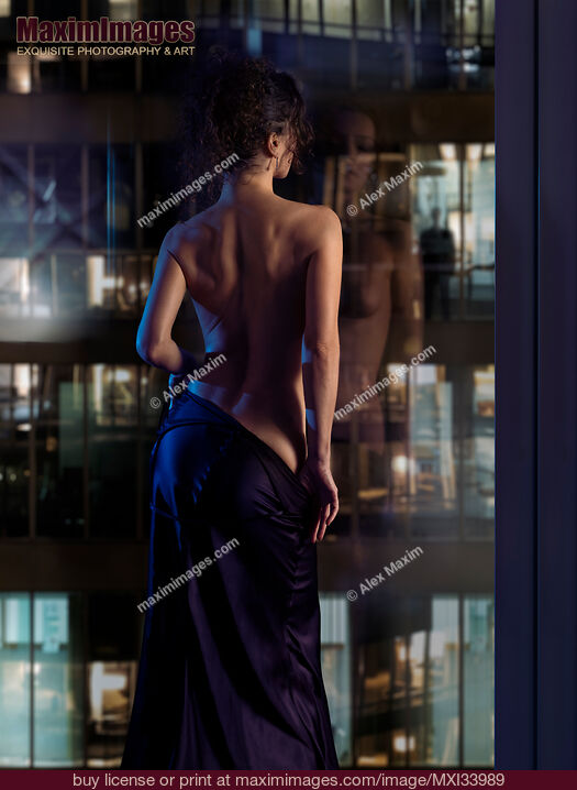 Stock photo of Beautiful sexy woman in undressing in front of a window with a man watching her seductive dance Buy commercial use license at MaximImages