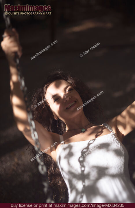 Stock photo of Young smiling woman riding on a swing Buy commercial use license at MaximImages