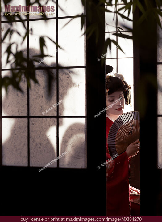 Stock photo of Beautiful caucasian lady, Japanese geisha with hand fan behind shoji screen of traditional Japanese house Buy commercial use license at MaximImages