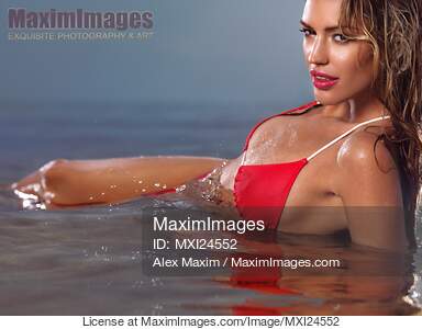 Young glamorous woman in red bikini lying in water... preview image