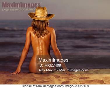 Naked woman sitting at the beach on sand... preview image