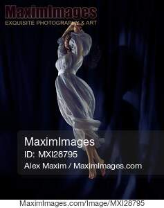 Young woman dancer spinning in the air in light blue dress... preview image