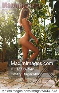 Beautiful sexy woman standing nude in an indoor greenhouse... preview image