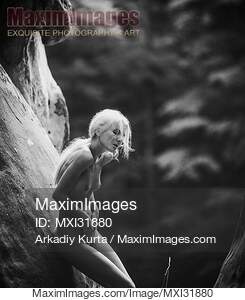 Nude woman with long white hair leaning against the rocks...... preview image