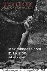 Nude woman gracefully leaning against rocks in the nature...... preview image