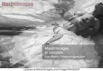 Beautiful nude woman lying in shiny water with her chest...... preview image
